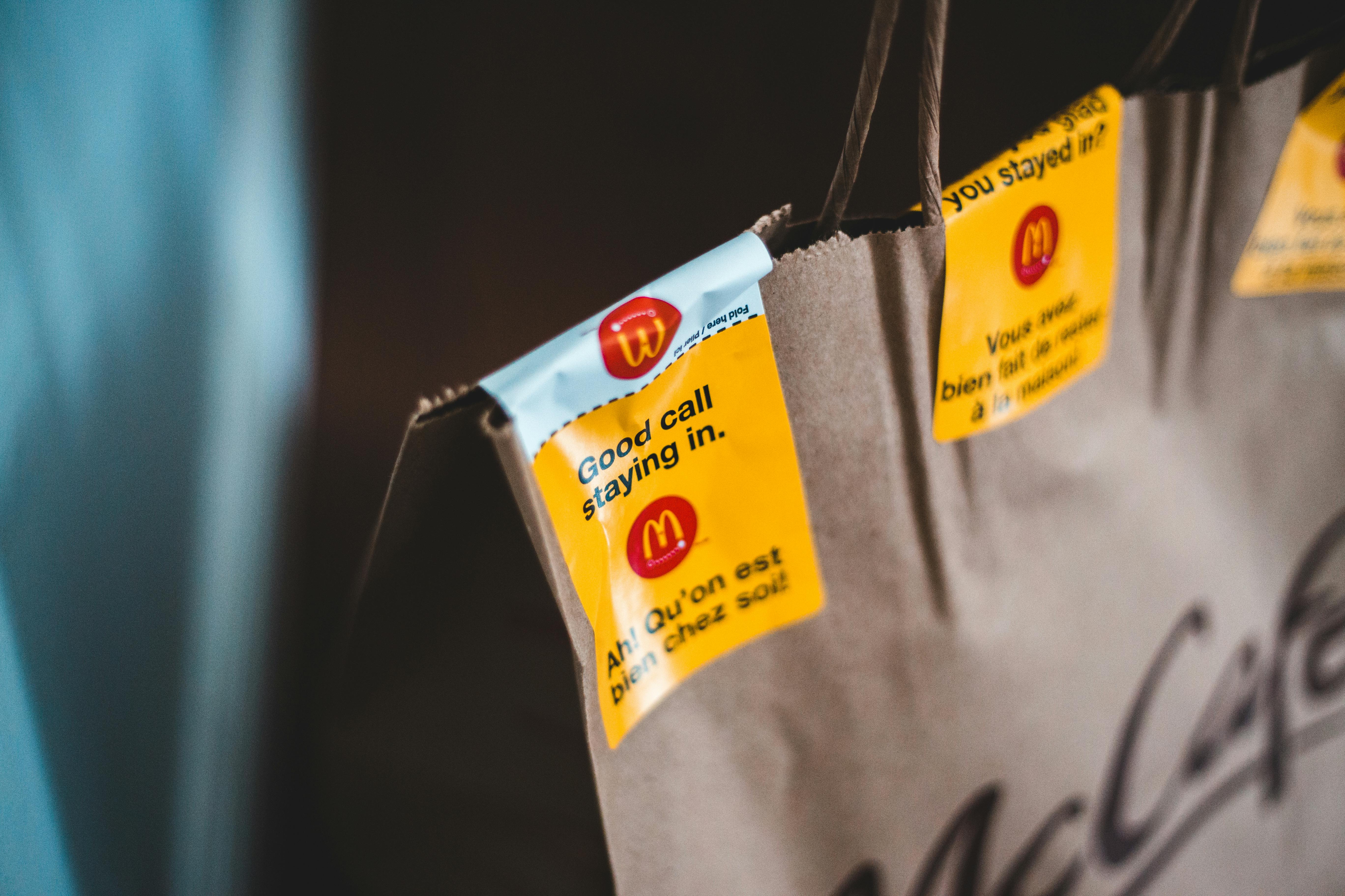 Close-up of a fast food paper bag with branding stickers and encouraging messages for takeout.