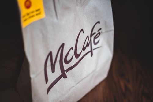 Free Close-up of a McCafé paper bag with a safety sticker, highlighting fast food takeout. Stock Photo