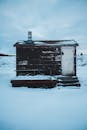 在冬日寒冷的天空下，一座孤独的木屋矗立在宁静的雪景中