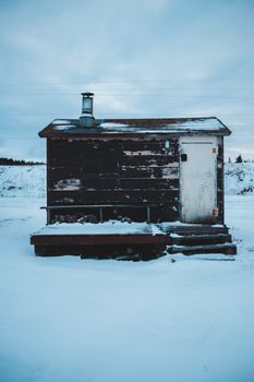 在冬日寒冷的天空下，一座孤独的木屋矗立在宁静的雪景中
