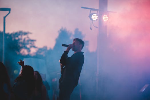 A dynamic live music performance featuring a singer on stage with vibrant lighting and fog effects.