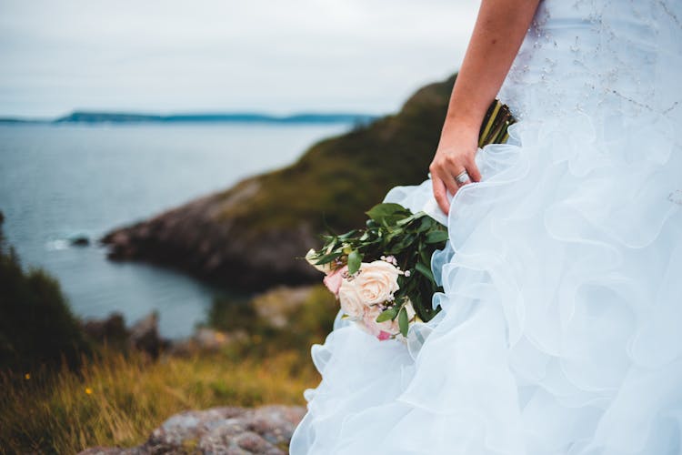 Crop Bride With Flowers Near Sea