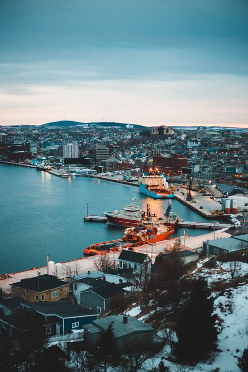 Free High-angle view of a coastal city harbor with ships and snow during twilight, capturing a serene winter evening. Stock Photo