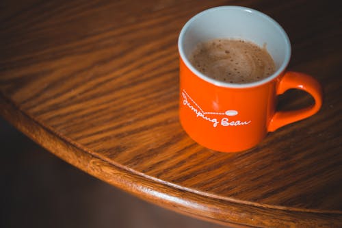 Free Orange Ceramic Mug on Brown Wooden Table Stock Photo