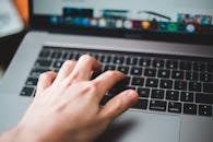 一只手在笔记本电脑键盘上打字的特写，展现了现代技术与数字创作