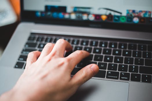 Close-up of a hand typing on a laptop keyboard, showcasing modern technology and digital work.