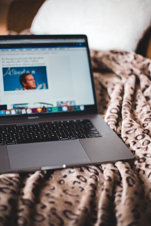 Free A laptop with a visible screen rests on a warm, animal print blanket, creating a cozy workspace ambiance. Stock Photo