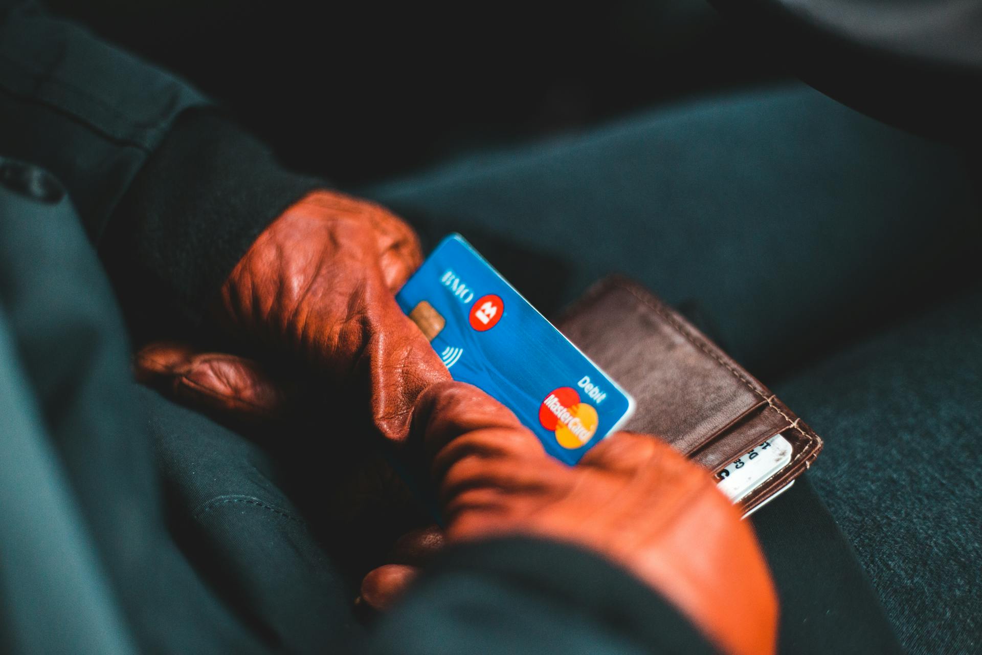 Close-up of hands in gloves holding a credit card and wallet indoors.