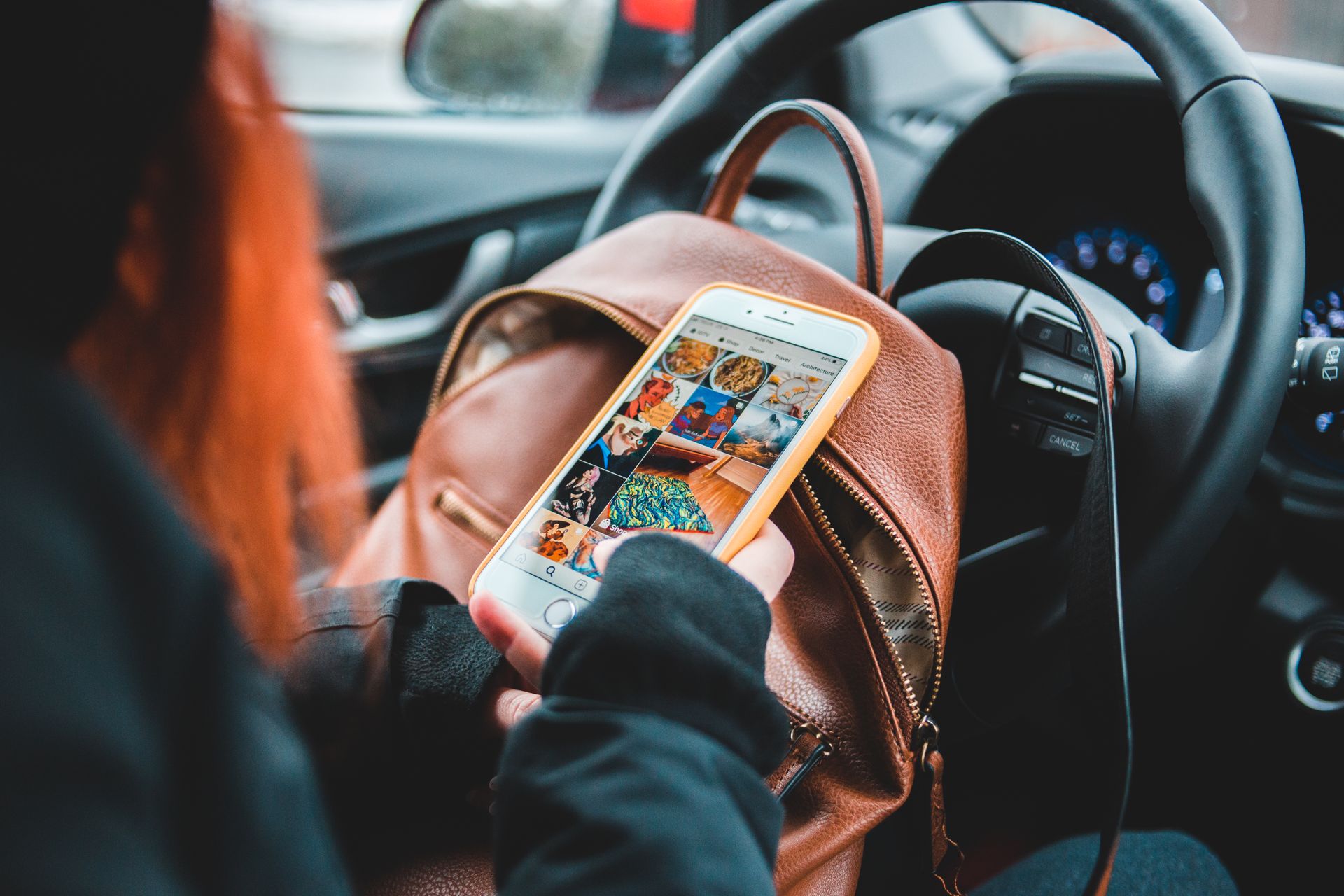 Person using a smartphone in a car while resting, engaging with social media.