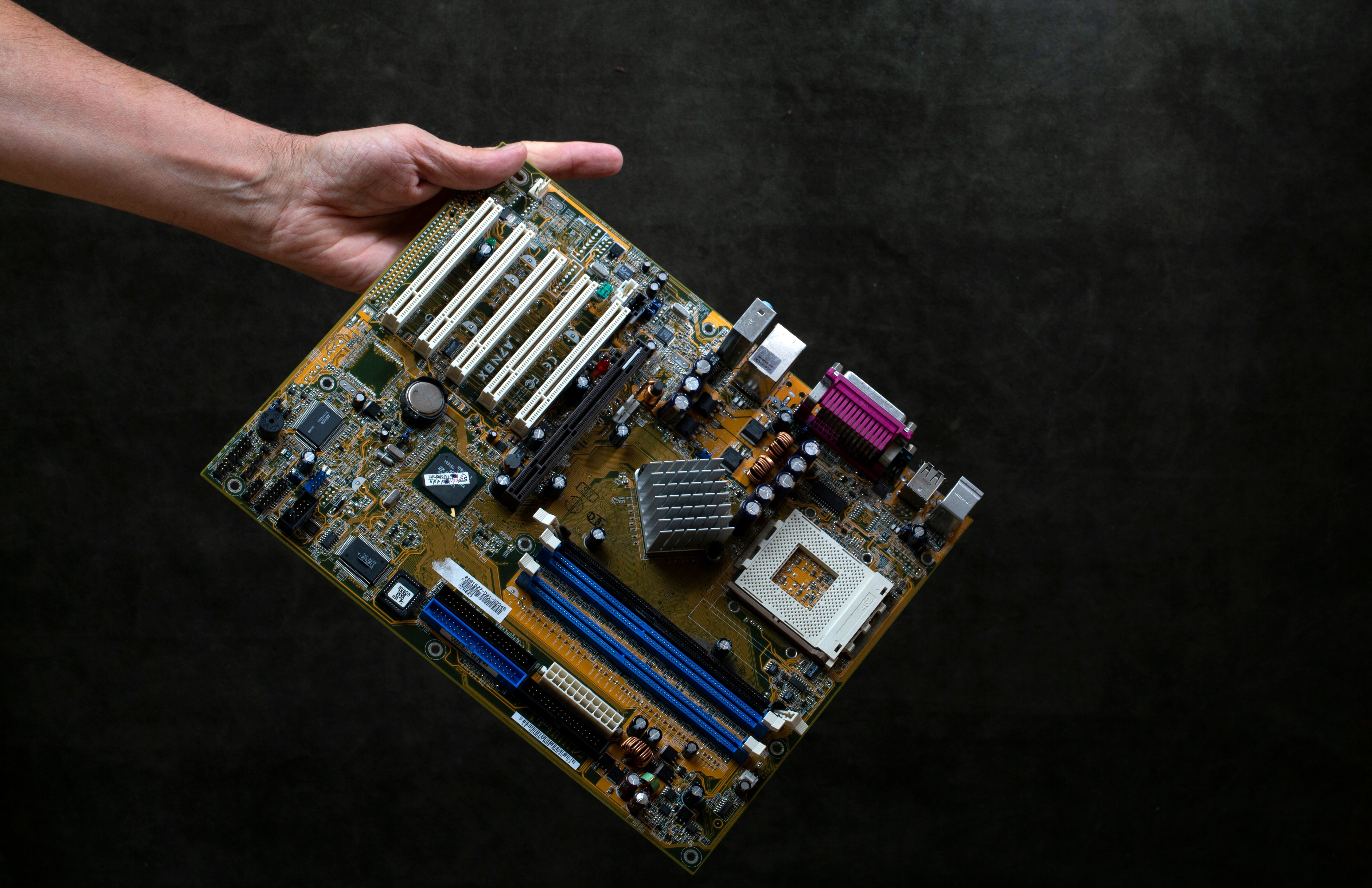 Person Holding Computer Motherboard on Dark Background · Free Stock Photo