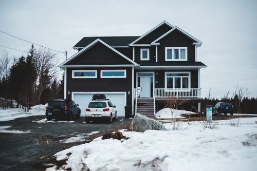 Free Facade of cottage with cars at garage in countryside covered with snow in winter season Stock Photo