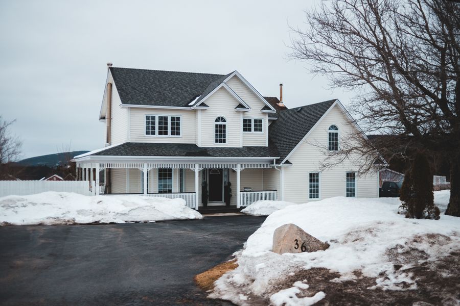 Exterior of modern cottage house with white facade in cold winter day with leafless trees in yard