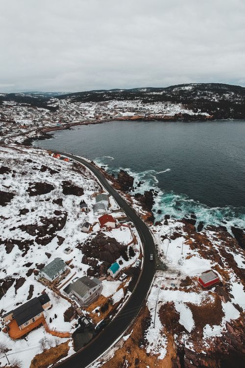 Free Drone view of paved route going through small town on shore of cold sea in gloomy day Stock Photo