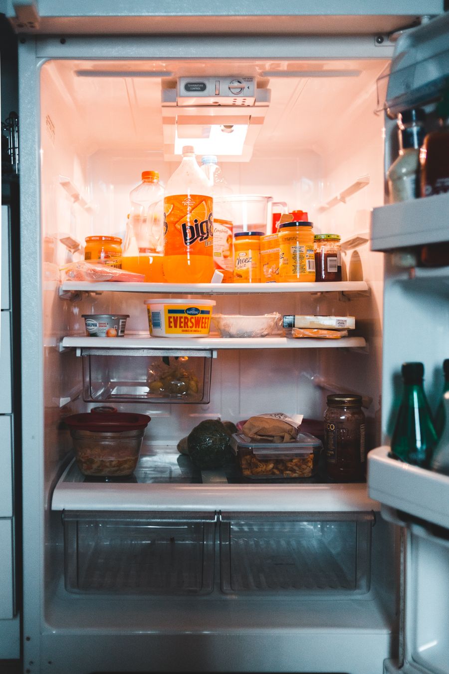 Open refrigerator interior stocked with food and beverages