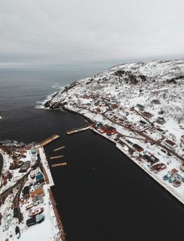 无人机将城市景观置于海岸，海湾在多云的北天空下封闭，眼前是一望无际的海洋