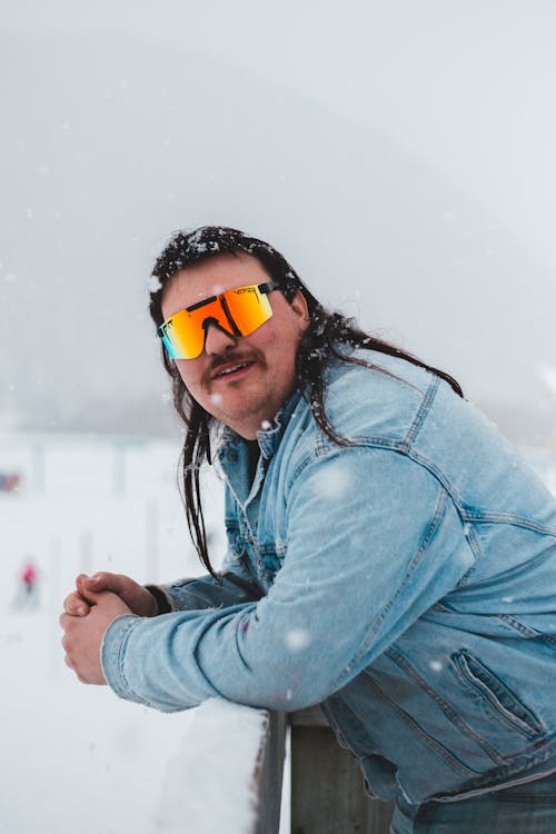 Foto Un hombre con gafas de sol y una chaqueta azul en la nieve