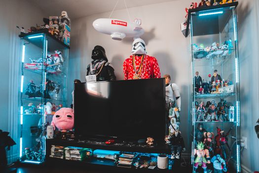 TV set surrounded with figurines and souvenir of comic character and movie heroes