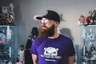 一个留着胡子、戴着太阳镜和帽子的男人站在摆满收藏雕像的房间里