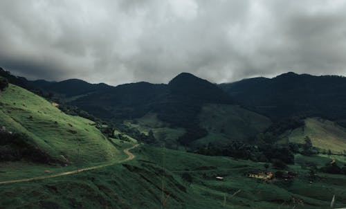 Green Grass Field and Mountain Under White Clouds