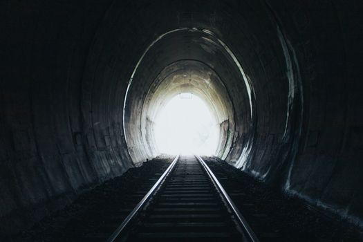 黑暗隧道内，铁轨延伸向明亮光线的迷人视角
