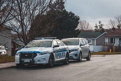Free A suburban street with a police car and parked vehicles. Captured in daylight. Stock Photo