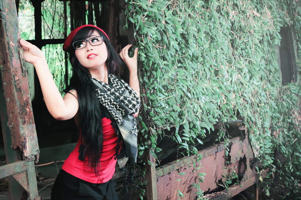 charming adult woman posing outdoors against ivy covered rustic backdr