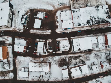 Captivating aerial view of snow-covered buildings and streets in a winter town, showcasing urban architecture and transportation.