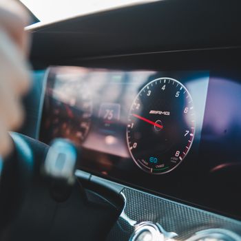 Close-up of a luxury car's digital dashboard featuring a speedometer and sleek interior design.