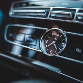Close-up image of a luxury car dashboard clock highlighting elegant automotive design.
