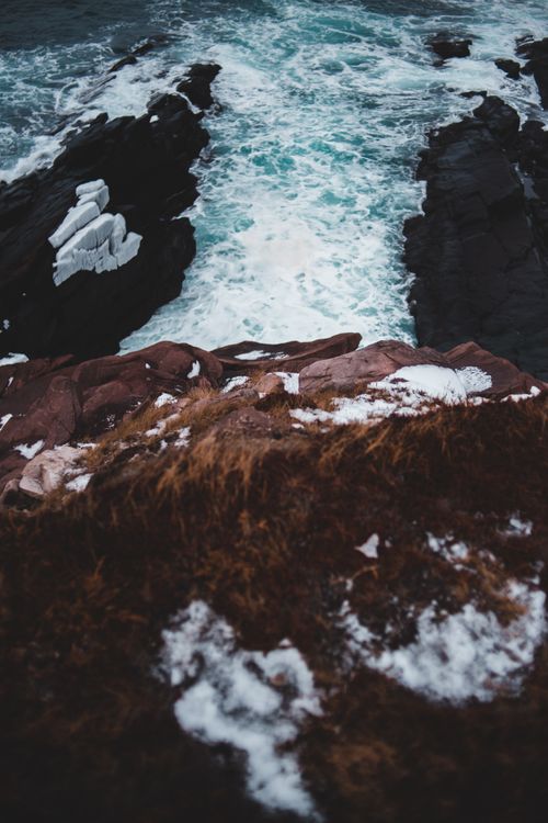 Free From above scenery view of rapid river flow with foam near rough slopes covered with faded grass and snow in afternoon Stock Photo