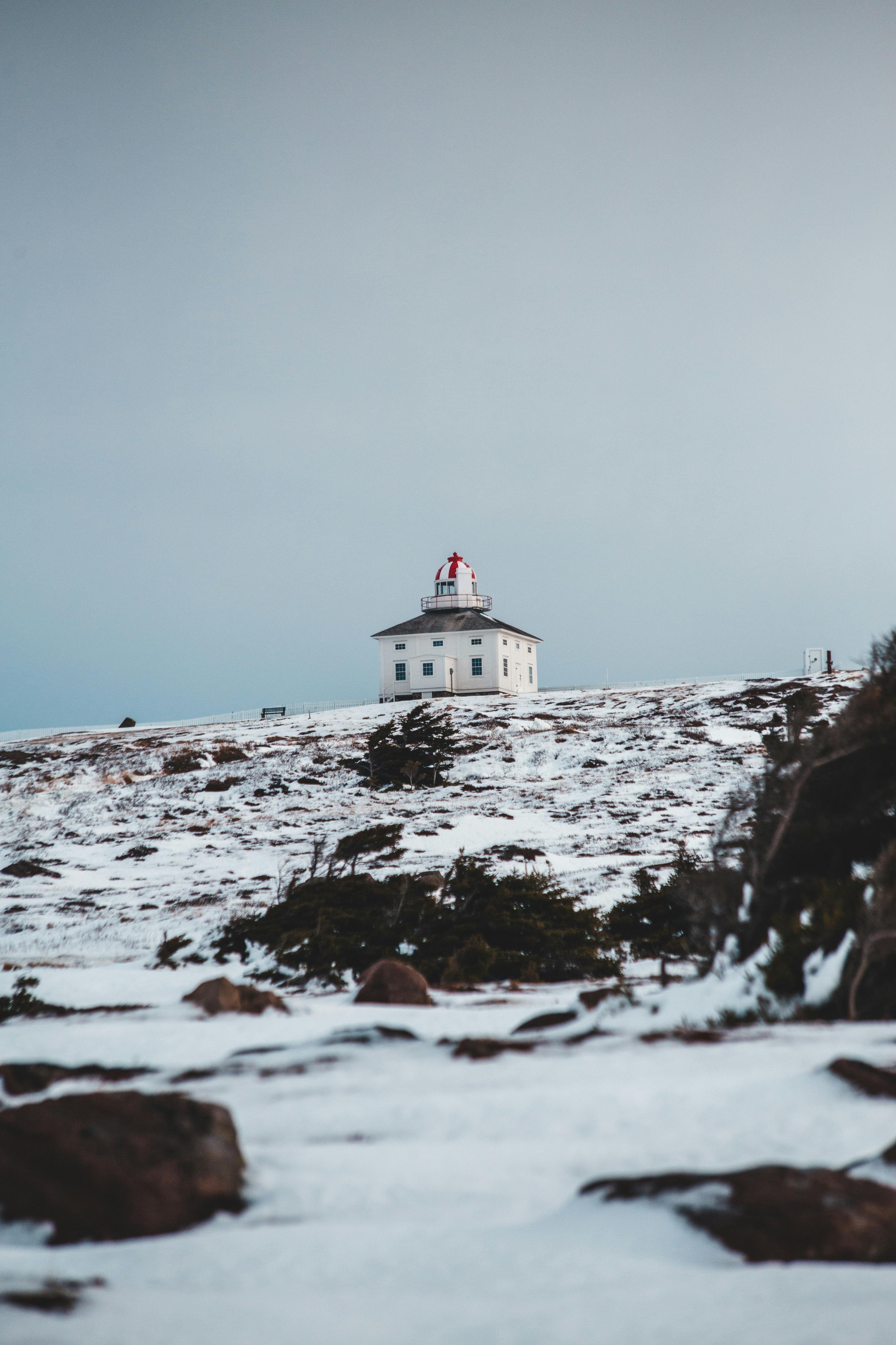 Free From above of old house on hill surrounded by snowy mounts under cloudy sky on foggy day Stock Photo