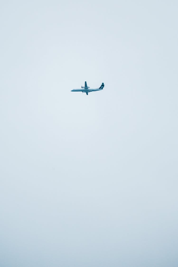 Modern Airplane Flying In White Sky