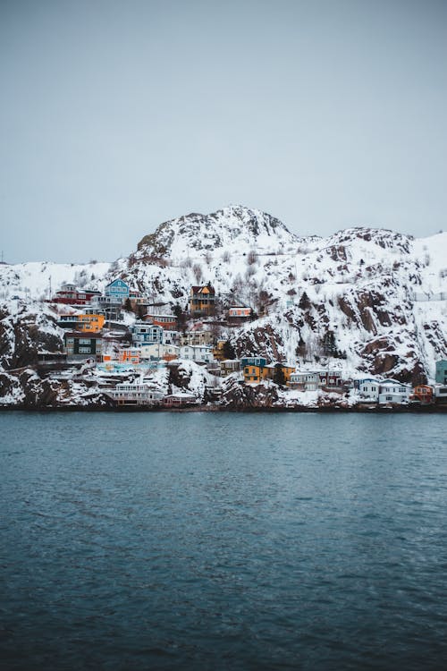 Houses on Snow Covered Mountain Near Body of Water