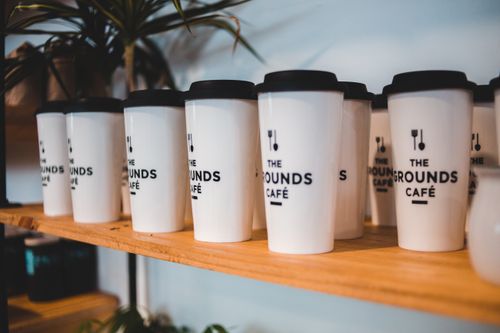 Free Designed white for coffee with black silicone lids and cutlery symbols on shelf for sale in coffee shop Stock Photo