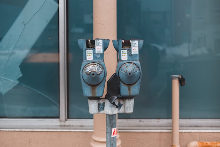 Aged Parking Meter Near Building Window On City Street