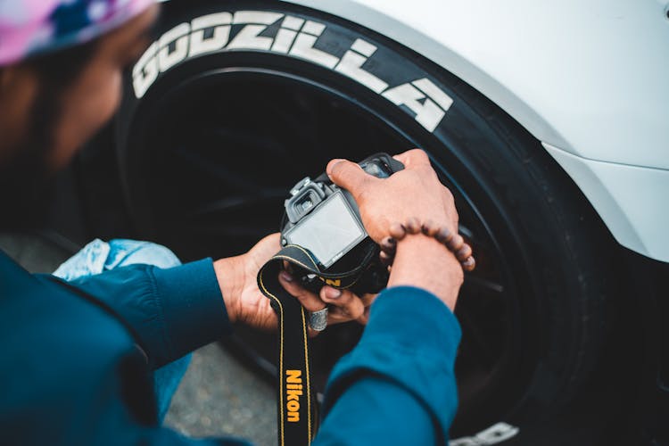 Crop Unrecognizable Man Taking Photo Of Car Wheel On Camera