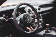 From above of modern style auto interior with steering wheel with buttons and klaxon near speedometer and hand brake in daylight