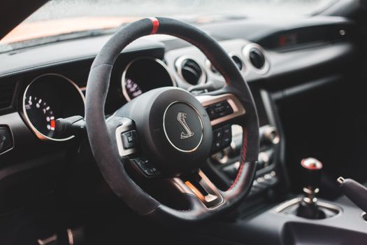From above of modern style auto interior with steering wheel with buttons and klaxon near speedometer and hand brake in daylight