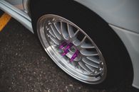 From above of contemporary design automobile wheel with purple stainless bolt spikes parked on asphalt pavement in daylight