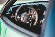 From above of contemporary design auto with lowered glass and plastic steering wheel with klaxon and buttons in center near speedometer and tachometer
