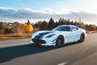 New sport car driving on road in countryside in autumn