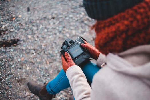 A woman in winter clothing holding a DSLR camera outdoors.