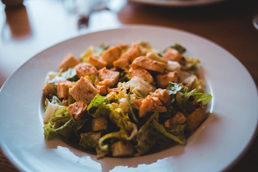 Mouth-watering Caesar salad with croutons and grilled chicken served on a white plate.