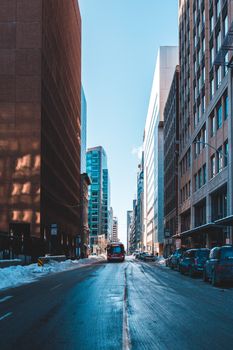 A city street flanked by skyscrapers, covered in snow, during winter.