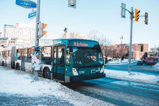 Urban bus navigating snowy streets at a city intersection during daytime winter.