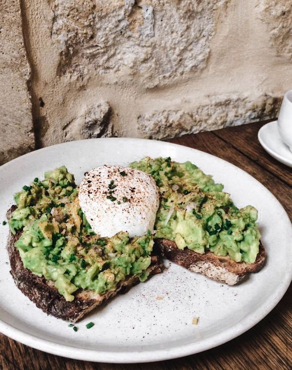 Avocado toast garni d'un œuf poché au jaune coulant sur pain grillé