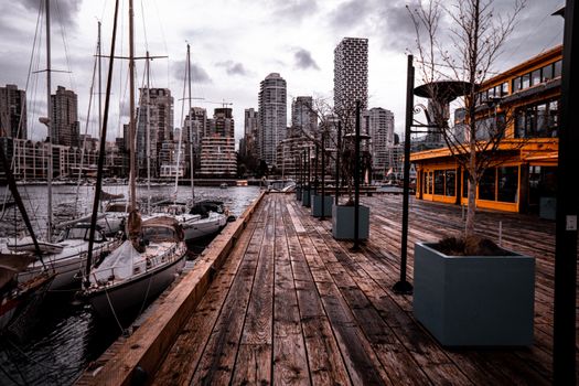 Vancouver harbor with sailboats and cityscape during twilight, showcasing urban architecture.