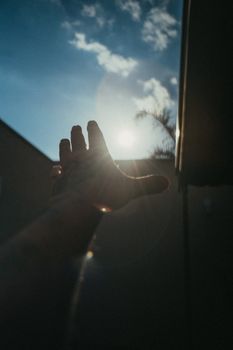 一只纹身的手伸向明亮的太阳，捕捉日光