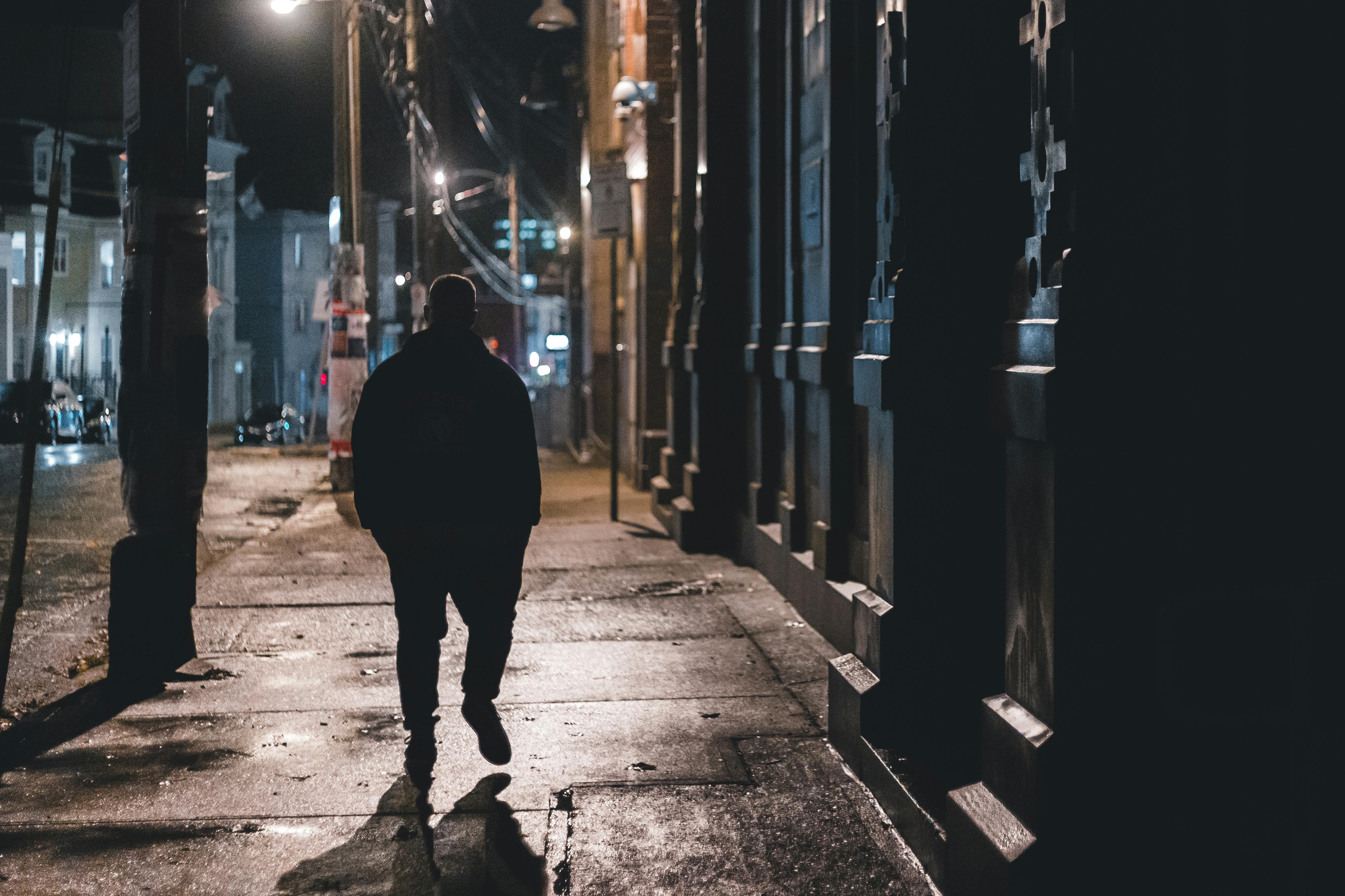 Man walking on sidewalk at night. | Photo: Pexels