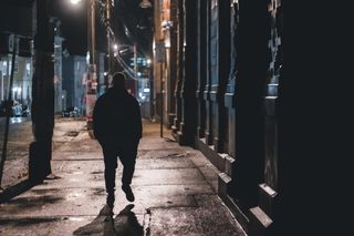 Silhouette of a person walking a wet street at night — Erik Mclean on Pexels